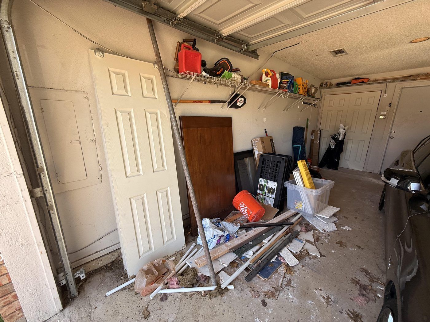 A real McKinney garage before a reset: doors, lumber, and boxes piled against the wall