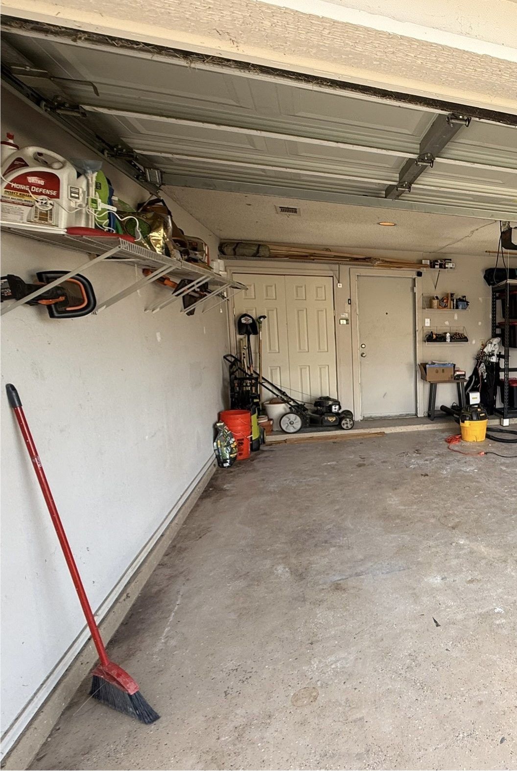 A real garage after a reset: swept floor, clear walking space, tools on wall racks