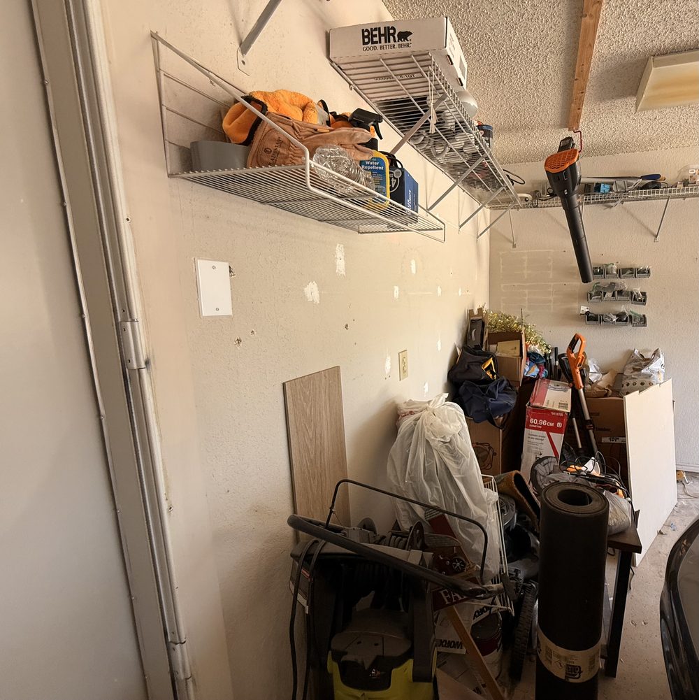 Real garage corner with household items, tools, and garage overflow before reset